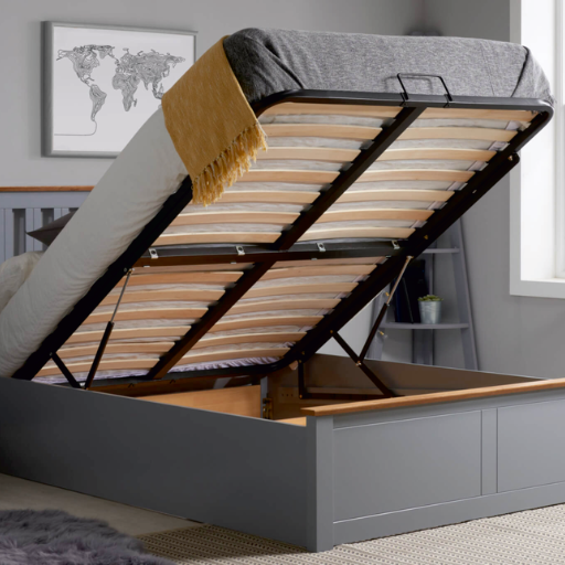 Kitchen pull-out drawer with chrome basket holding black bottles, white cabinetry, and gray floor